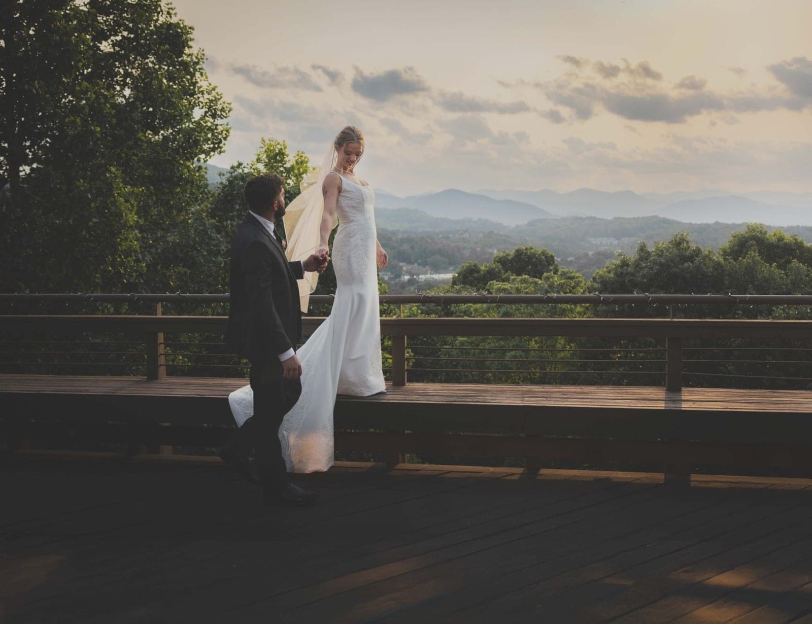 A bride and groom on a mountain overlook at sunset